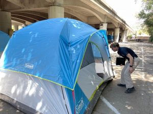 case worker visiting tent under freeway